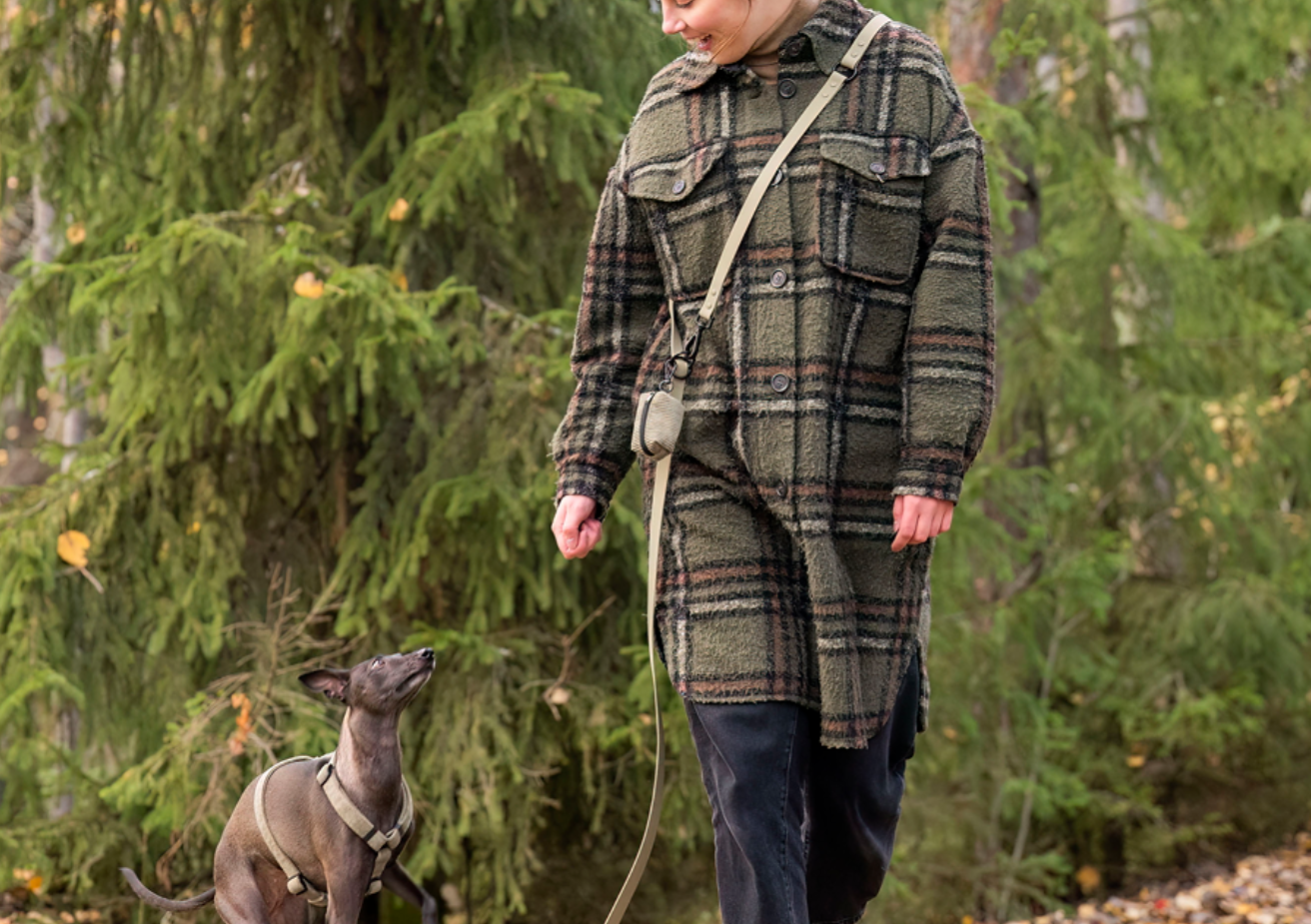 Koira ja ihminen metsäkävelyllä Woofyn monitoimihihna ja kakkapussipidike käytössä.